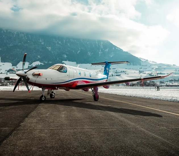 PC-12 aircraft in RFDS colours on tarmac surrounded by snow and moutains